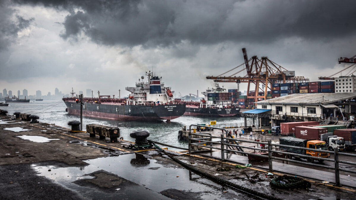 Bustling port in Mumbai with oil tankers and cargo ships under overcast sky