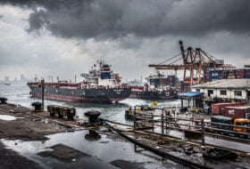 Bustling port in Mumbai with oil tankers and cargo ships under overcast sky