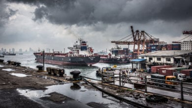 Bustling port in Mumbai with oil tankers and cargo ships under overcast sky
