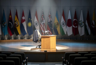 Defense Secretary Hegseth at a podium in Singapore with Indo-Pacific flags