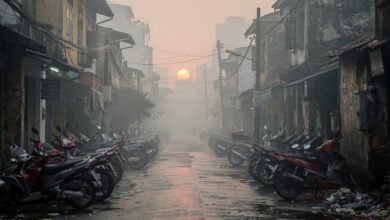 Hanoi street shrouded in smog with parked motorbikes and scooters, heavy air pollution