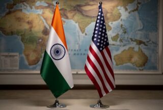 Indian and US flags with blurred map of Strait of Hormuz in background
