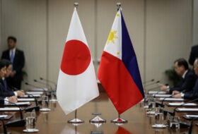 Japanese and Philippine flags at formal Tokyo summit table, diplomatic setting