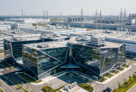 Modern glass campus in Taipei technology park with semiconductor fabs visible in background
