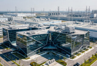 Modern glass campus in Taipei technology park with semiconductor fabs visible in background