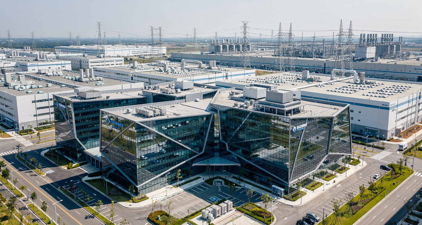 Modern glass campus in Taipei technology park with semiconductor fabs visible in background