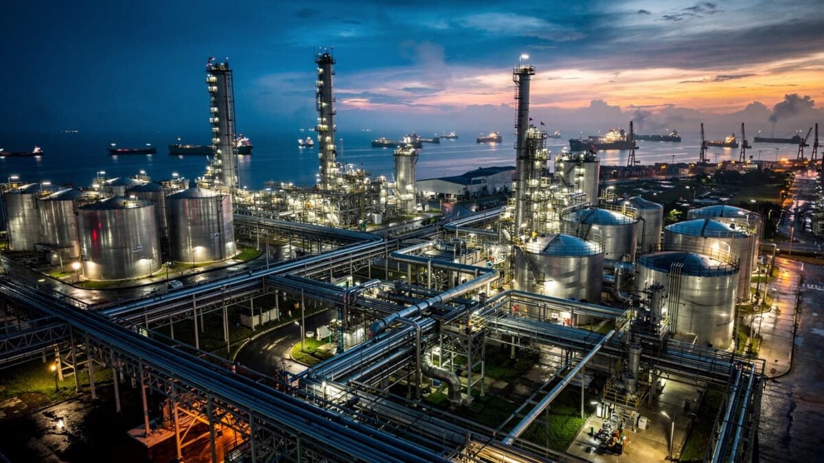 Oil refinery and port at dusk in Southeast Asia with pipelines and tanks