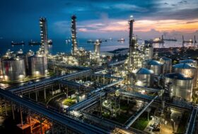 Oil refinery and port at dusk in Southeast Asia with pipelines and tanks