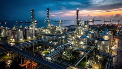 Oil refinery and port at dusk in Southeast Asia with pipelines and tanks