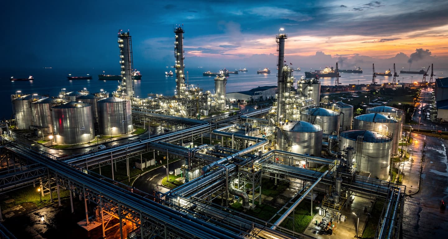 Oil refinery and port at dusk in Southeast Asia with pipelines and tanks