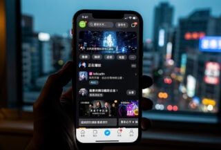 Smartphone displaying Chinese streaming app with Taipei skyline in background