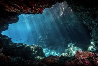 Underwater cave entrance in Vaavu Atoll, Maldives, with dramatic lighting