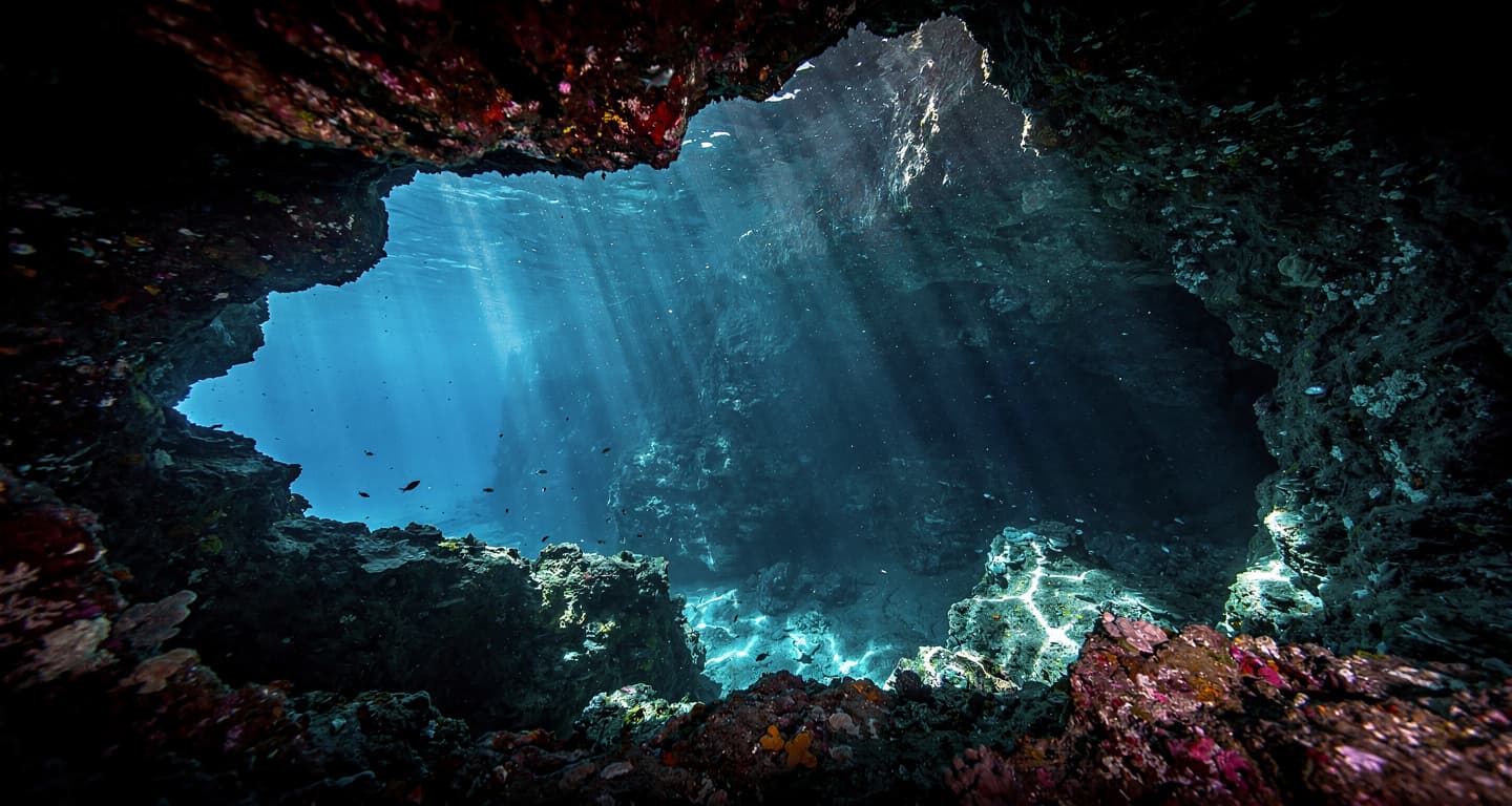 Underwater cave entrance in Vaavu Atoll, Maldives, with dramatic lighting