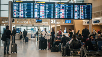 Airport departure board showing flight cancellations, Gulf hub terminal, travellers with luggage
