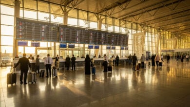 Airport departure hall in Dubai with check-in counters and departure boards, afternoon light