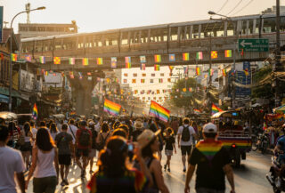 Bangkok Pride festival street scene with rainbow flags and crowds during daytime