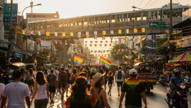 Bangkok Pride festival street scene with rainbow flags and crowds during daytime