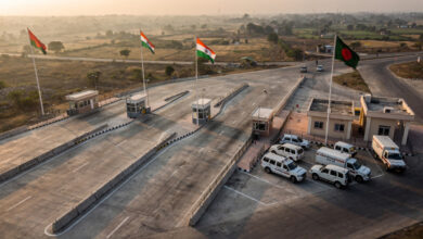 Border checkpoint between India and Bangladesh with concrete barriers and flags at dawn