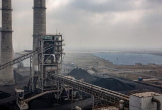 Coal power plant with solar panels in background, northern India industrial landscape