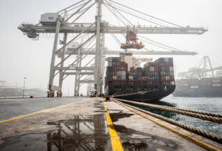 Container ship at Gulf port terminal with industrial cranes and stacked cargo containers