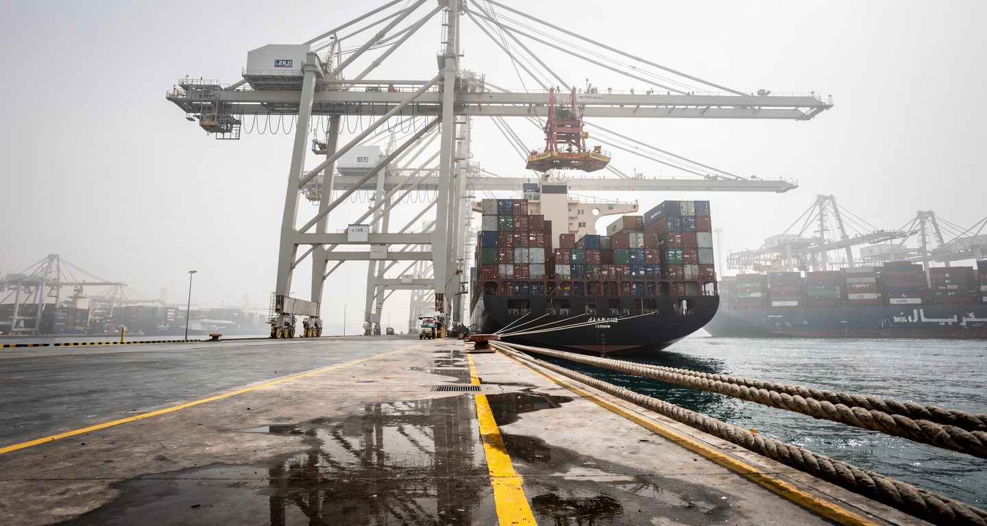 Container ship at Gulf port terminal with industrial cranes and stacked cargo containers