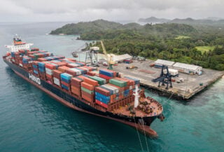 Container ship at small Pacific island port with stacked cargo containers