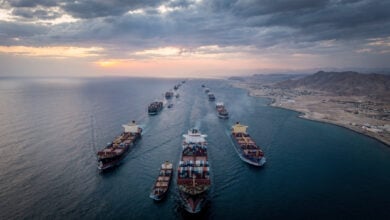 Container ships transiting Strait of Hormuz at dawn, narrow waterway between Iran and Gulf states