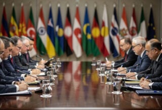 Defence ministers at formal conference table, Singapore, flags of Asian nations in background