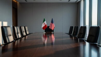Empty negotiation table in Swiss conference room with Iranian and US flags