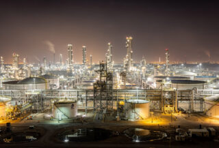 Illuminated oil refinery and storage tanks at night, Persian Gulf industrial complex