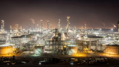 Illuminated oil refinery and storage tanks at night, Persian Gulf industrial complex