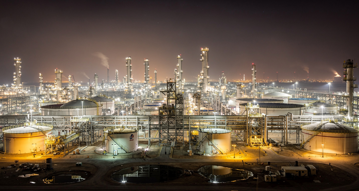 Illuminated oil refinery and storage tanks at night, Persian Gulf industrial complex