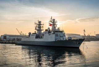 Modern military frigate docked at Manila naval base with Philippine flag