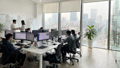 Modern tech office interior in Hanoi with engineers at workstations and city skyline