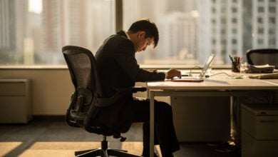 Office worker at desk, face turned away, modern corporate workspace with afternoon light