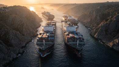 Oil tankers navigating narrow strait between rocky coastlines at dawn, aerial view
