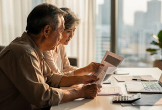 Older couple reviewing retirement documents in modern Asian apartment with city view