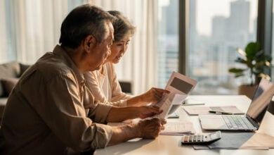 Older couple reviewing retirement documents in modern Asian apartment with city view