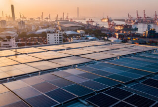 Rooftop solar panels overlooking industrial port city at dusk, Southeast Asia