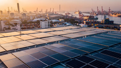 Rooftop solar panels overlooking industrial port city at dusk, Southeast Asia