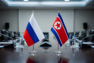 Russian and North Korean flags on diplomatic meeting table, formal government setting