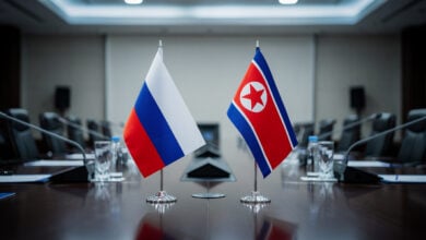 Russian and North Korean flags on diplomatic meeting table, formal government setting
