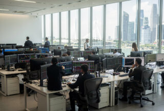 Singapore financial trading floor with multiple screens and Marina Bay skyline view