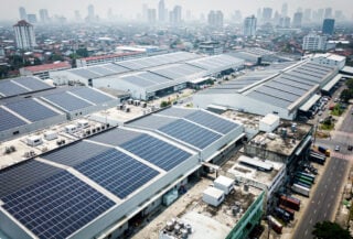 Solar panel arrays covering industrial rooftops in Southeast Asian city