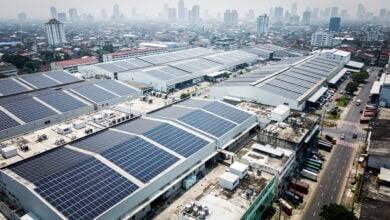Solar panel arrays covering industrial rooftops in Southeast Asian city