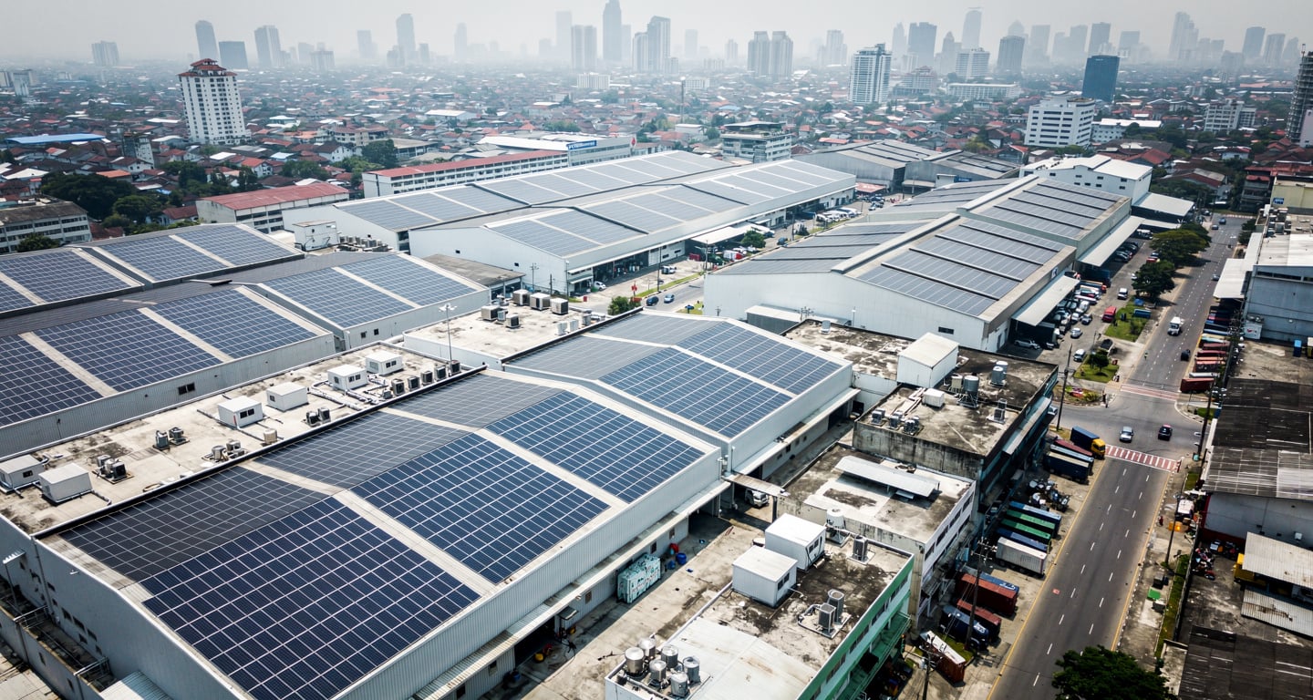 Solar panel arrays covering industrial rooftops in Southeast Asian city