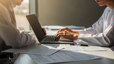 Student at desk with exam papers and laptop, Middle East office setting