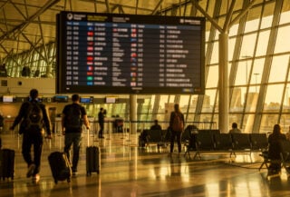 Sydney airport departure board showing Asian destinations, modern terminal with travellers