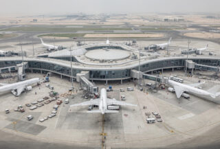 Wide-body aircraft at modern airport terminal gate in Gulf hub, daytime overcast lighting
