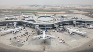 Wide-body aircraft at modern airport terminal gate in Gulf hub, daytime overcast lighting